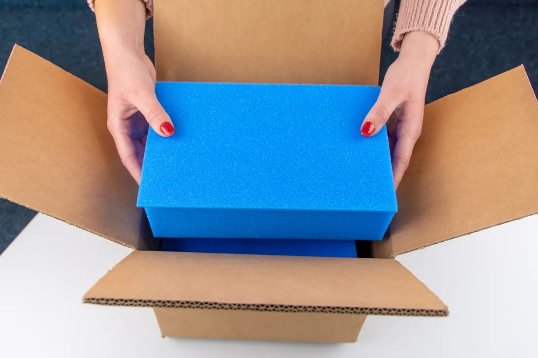 Präzisionsteile werden geschützt in einer blauen Schaumstoff-Verpackung im Versandkarton platziert