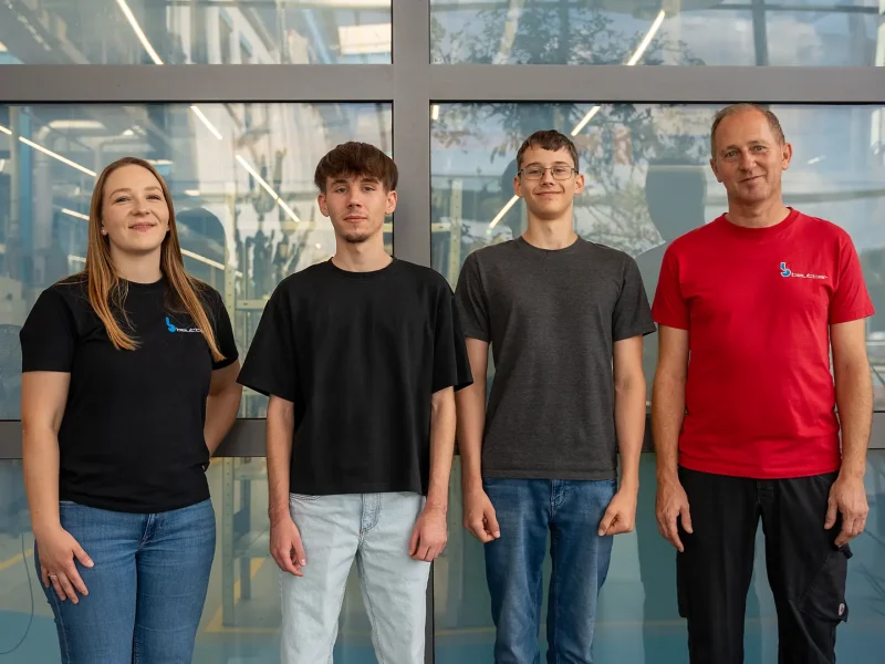 Vier Personen in BEUTTER-Shirts vor der Glasfront der Fertigungshalle – Begrüßung der neuen Azubis 2026.